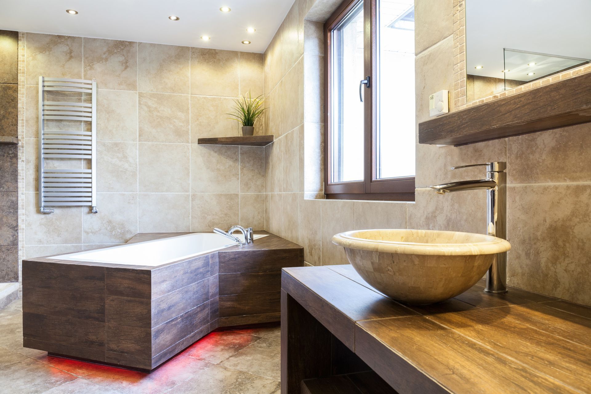 renovated bathroom with angled tub and wall and floor tiling with raised sink