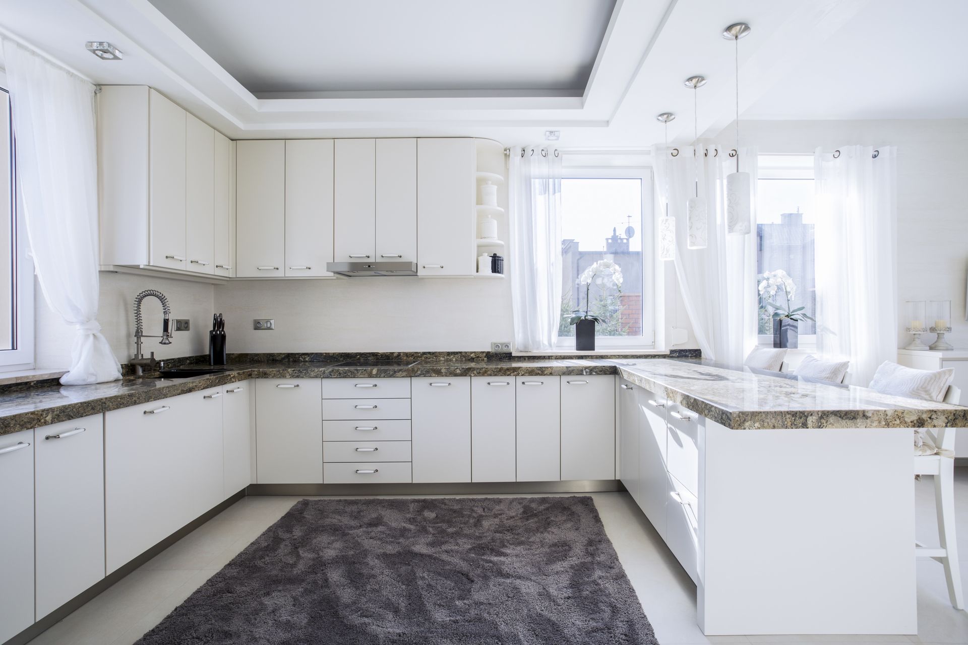 renovated open kitchen with white cabinets and dark quartz counters