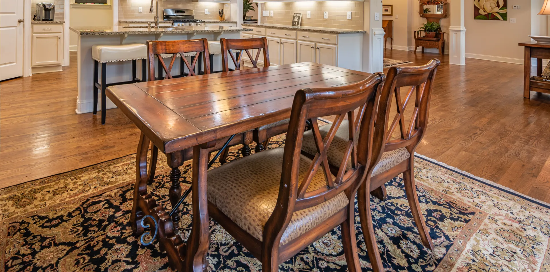 A dining room table and chairs in a house with a rug on the floor.