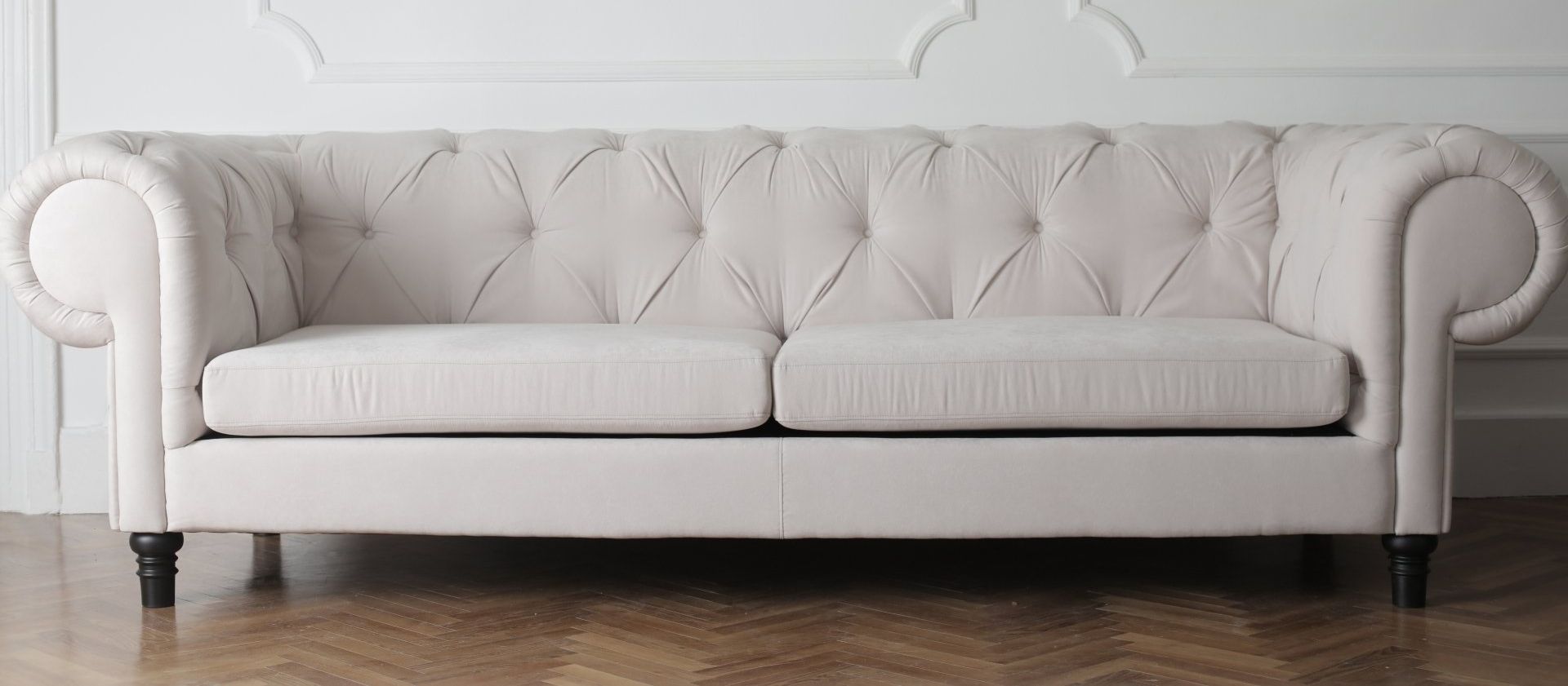 A white couch is sitting on a wooden floor in a living room.