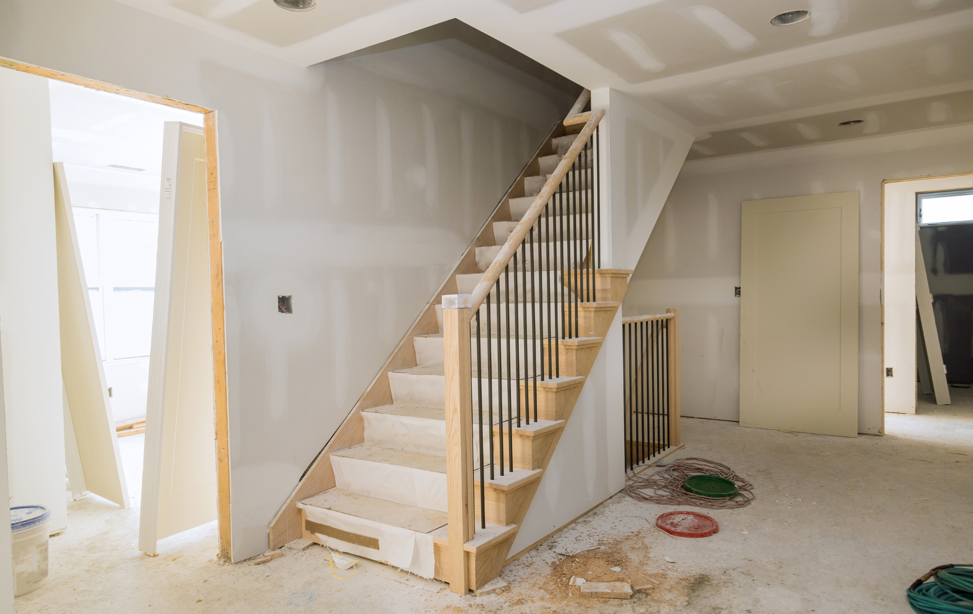 Interior view of a staircase during construction, showing unfinished walls, stairs, and railing.