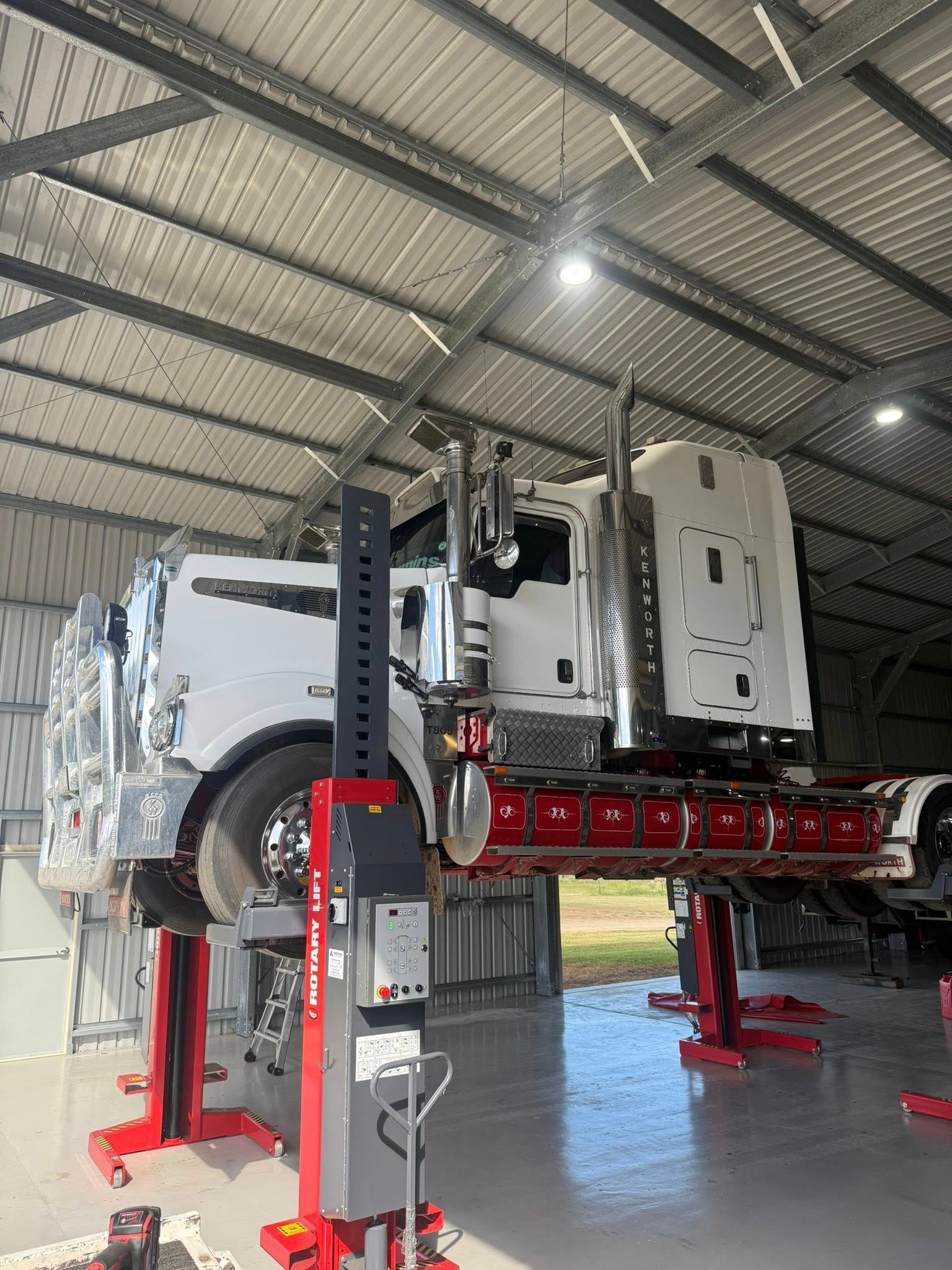 A White Semi-truck Raised on Red Hydraulic Lifts — Full Torque Transport In Parkhurst, QLD
