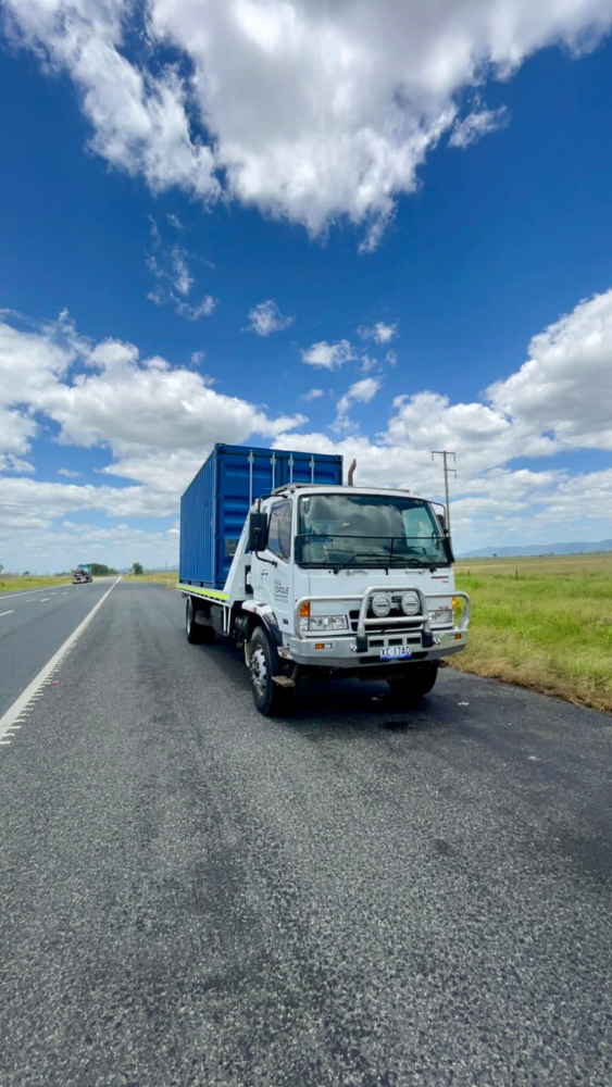 White cargo truck with blue container parked on a roadside under a bright cloudy sky.— Full Torque Transport In Parkhurst, QLD