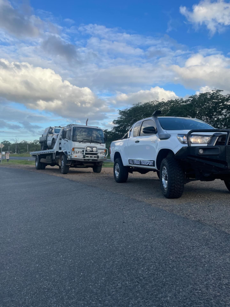 Two trucks parked on a roadside under a partly cloudy sky, one white and one flatbed.— Full Torque Transport In Parkhurst, QLD