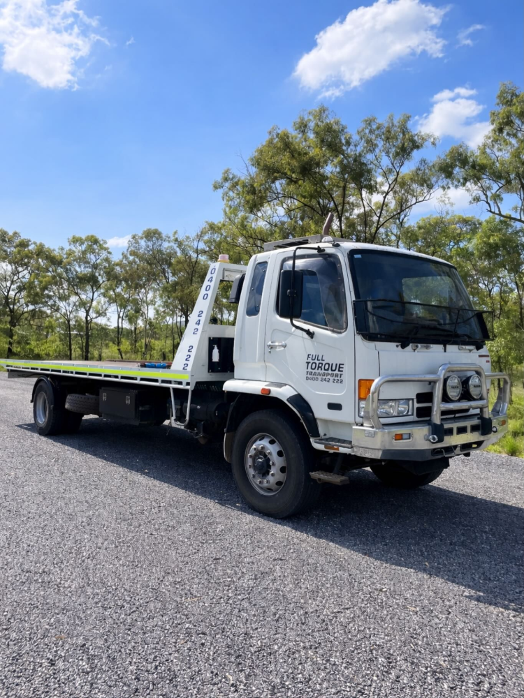 White flatbed tow truck parked on gravel road with trees and blue sky in the background— Full Torque Transport In Parkhurst, QLD
