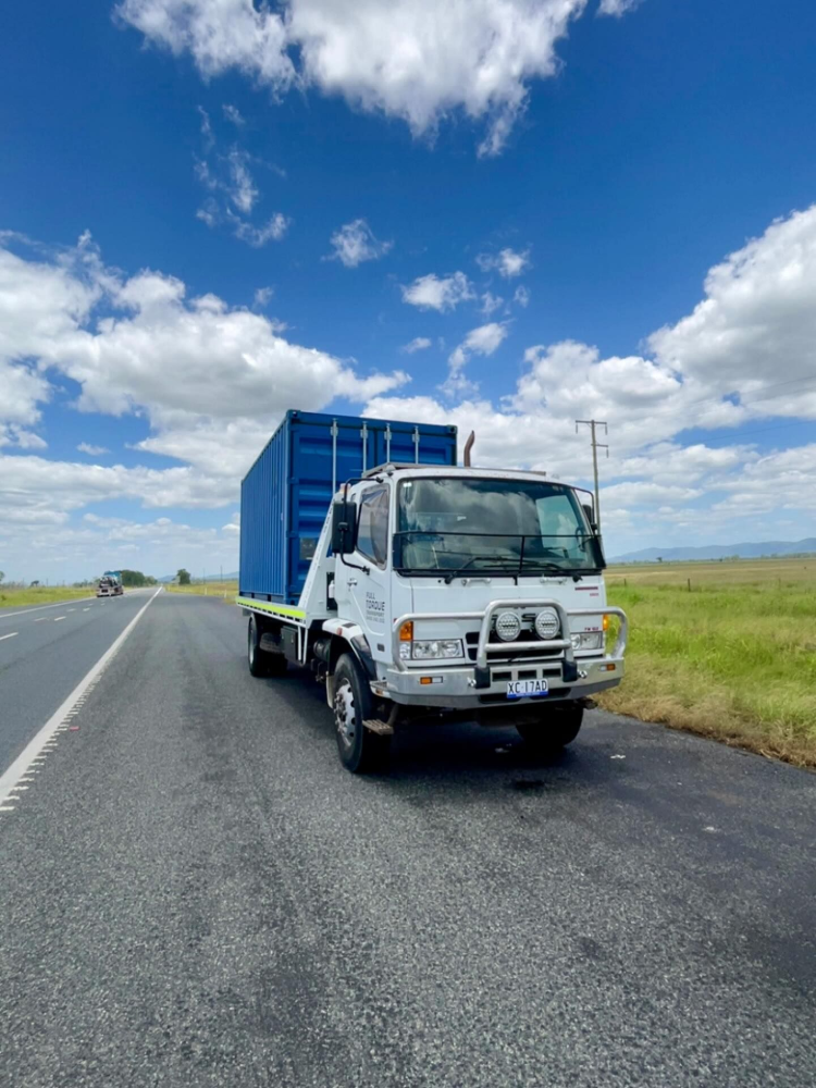 White flatbed truck with blue cargo container parked on a rural road under a bright blue sky— Full Torque Transport In Parkhurst, QLD