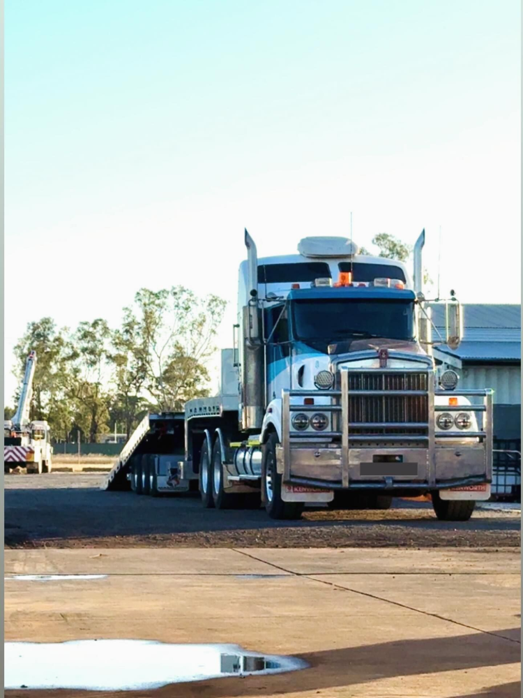 Blue semi-truck parked on a flatbed trailer in an open lot under a clear sky— Full Torque Transport In Parkhurst, QLD