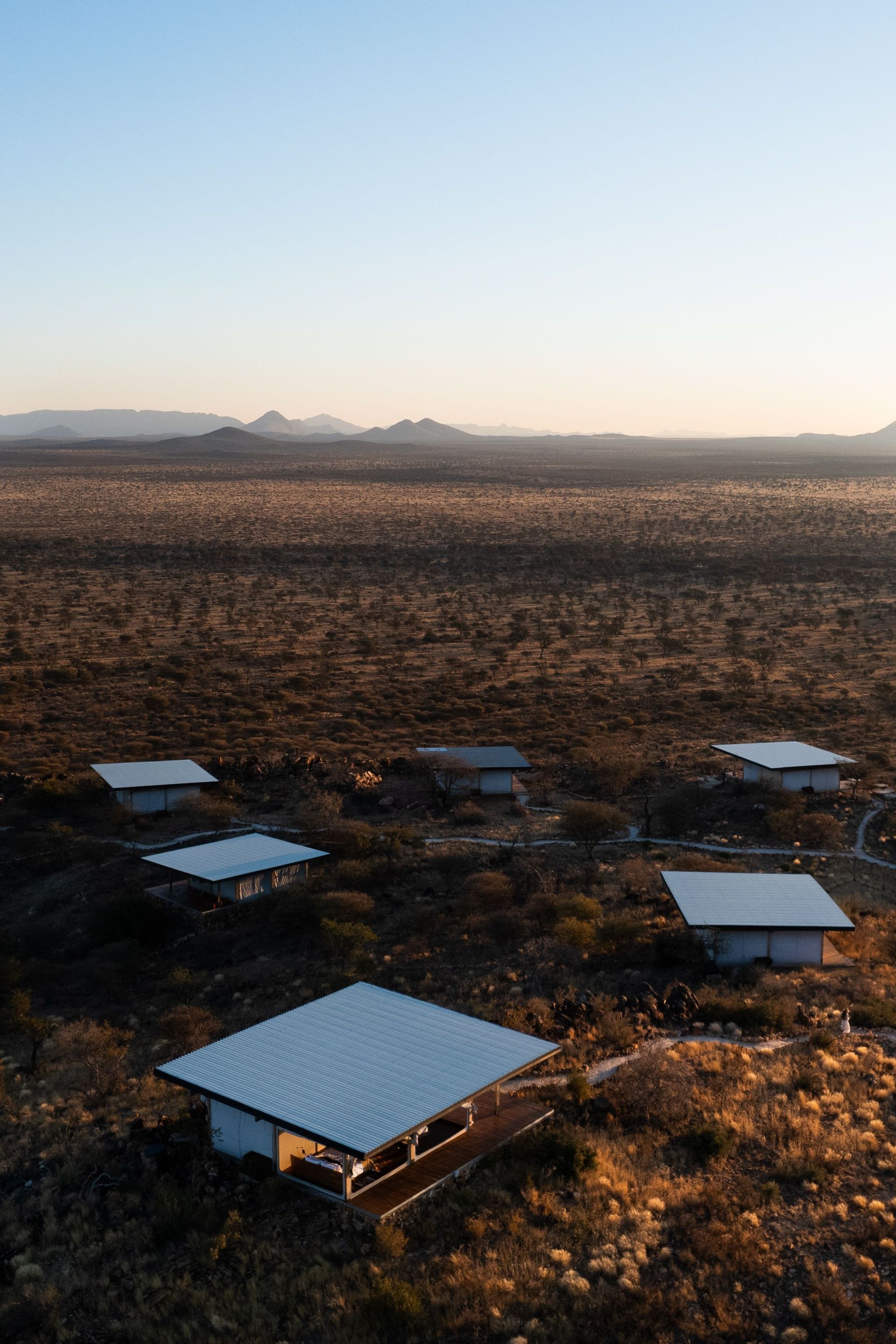 Outdoor seating platforms in a dry field at sunset, with mountains in the distance