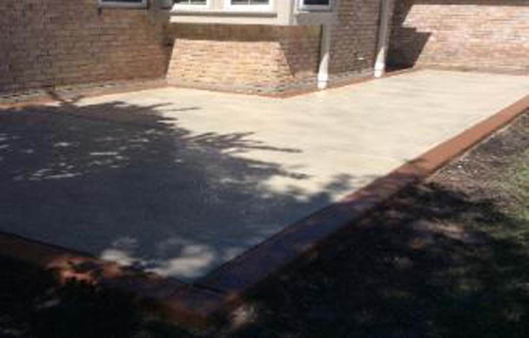 A brick house with a concrete patio in front of it.