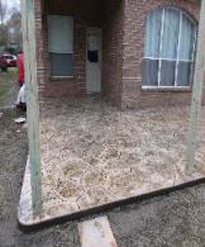 A brick house with a concrete porch in front of it.