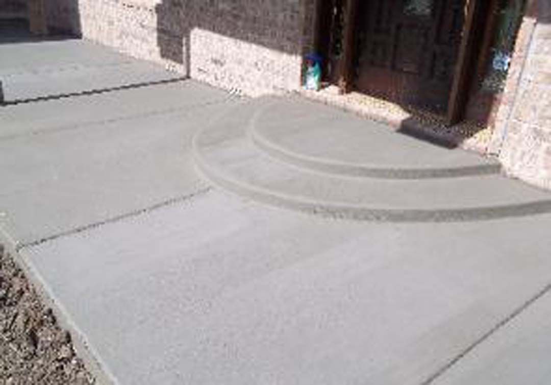 A concrete walkway with steps leading up to a house.