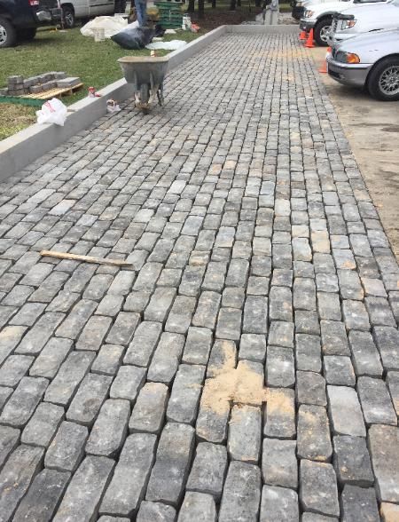 A brick walkway with a wheelbarrow on the side of it