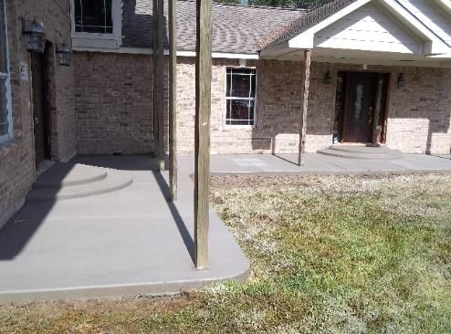 A brick house with a concrete porch in front of it.