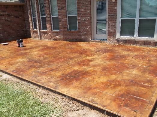 A stained concrete patio in front of a brick house.