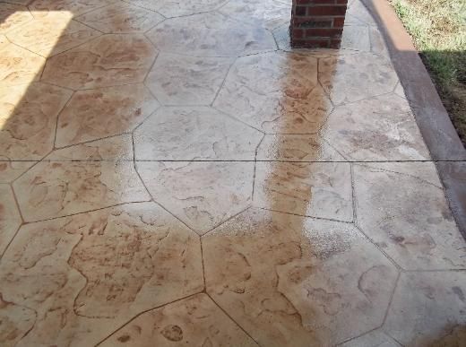 A close up of a concrete floor with a brick wall in the background.
