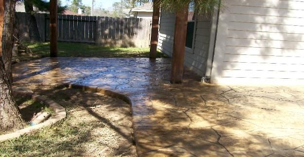 A concrete walkway leading to a garage in a backyard.