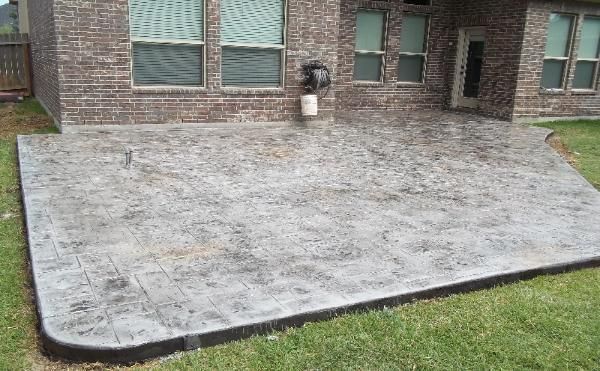A brick house with a concrete patio in front of it.