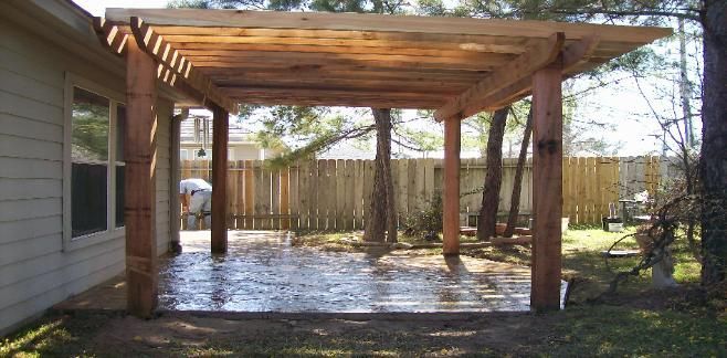 A wooden pergola is in the backyard of a house.