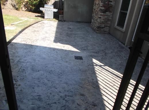 A patio with a grill and a fence in the background.