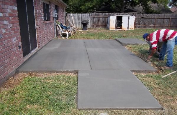 A man in a red and white striped shirt is working on a concrete walkway