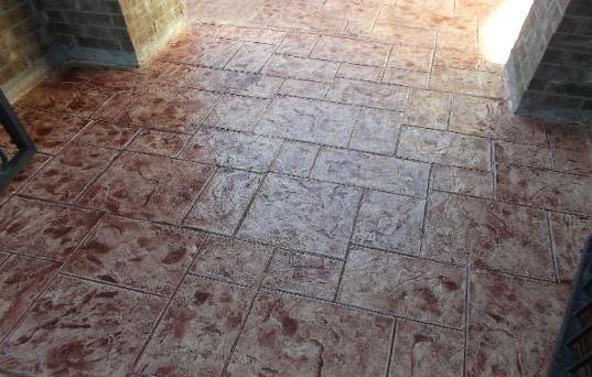 A close up of a brick floor with a fence in the background.