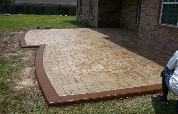 A brick house with a concrete patio in front of it.