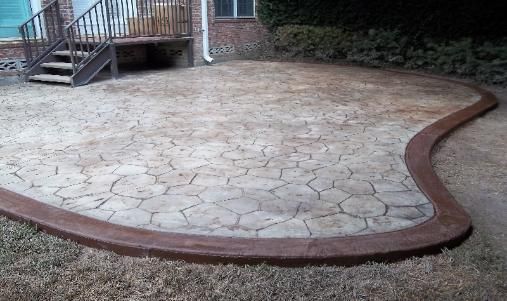 A concrete patio with a curved border in front of a house.