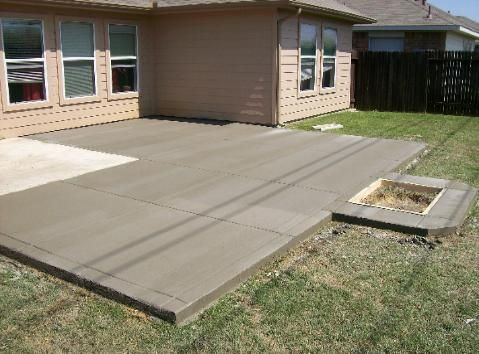 A concrete patio with a fire pit in the backyard of a house.