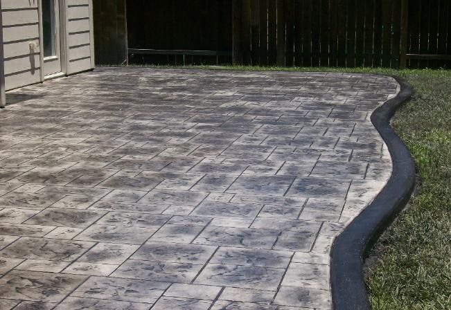 A patio with a black border and a fence in the background