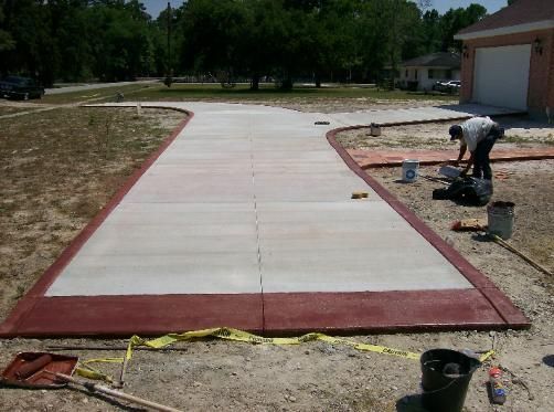 A man is working on a concrete driveway in front of a garage