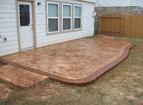 A concrete patio in front of a house with a wooden fence.
