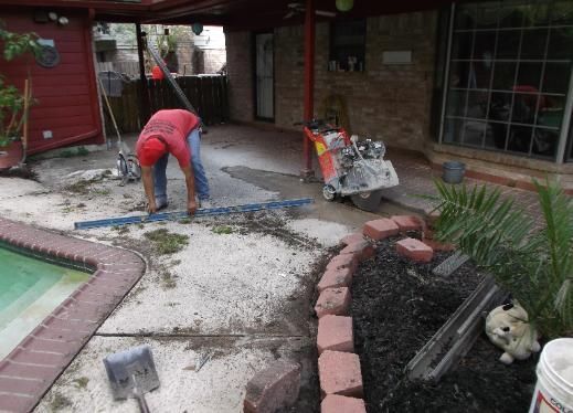 A man is working on a patio next to a pool.