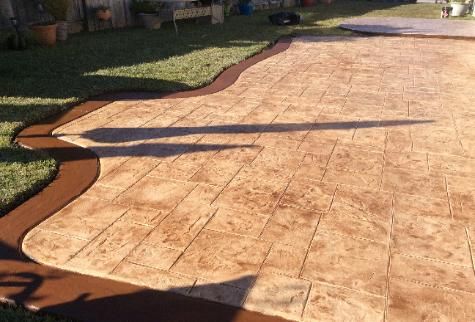 A concrete driveway with a brown border and a shadow on the ground.
