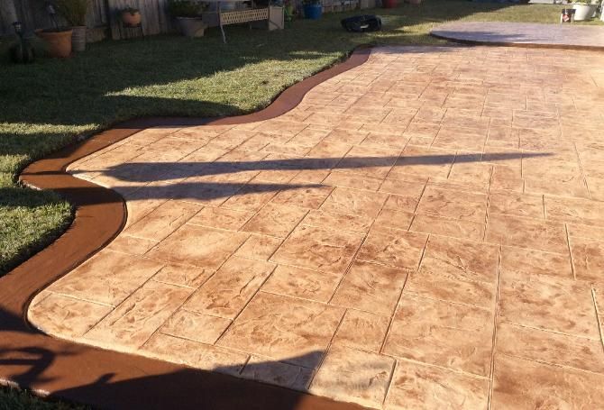 A concrete driveway with a brown border and a shadow on the ground.