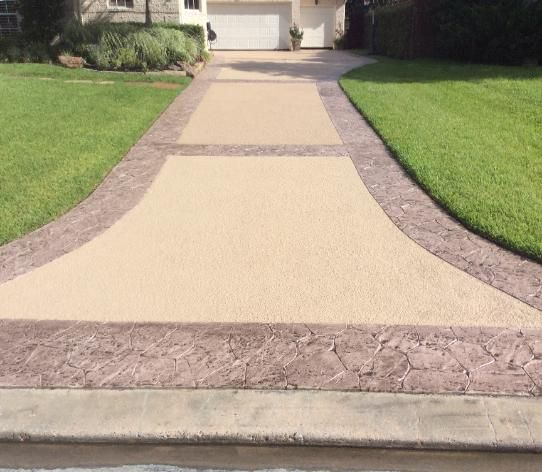 A driveway leading to a house with a lush green lawn.