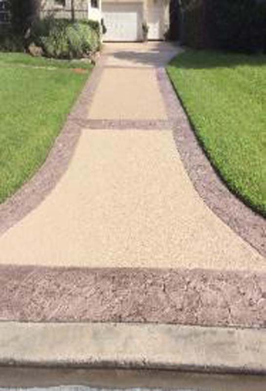 A walkway leading to a house with a lush green lawn.