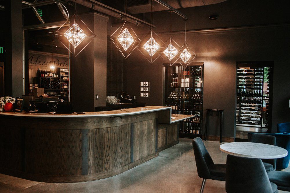 Stylish bar interior with wooden counter, wine display, and diamond-shaped pendant lights.