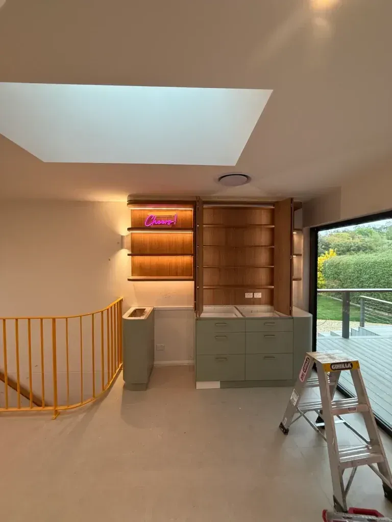 Built-in bookshelves and cabinets in a light-filled room with a skylight, featuring a yellow railing.