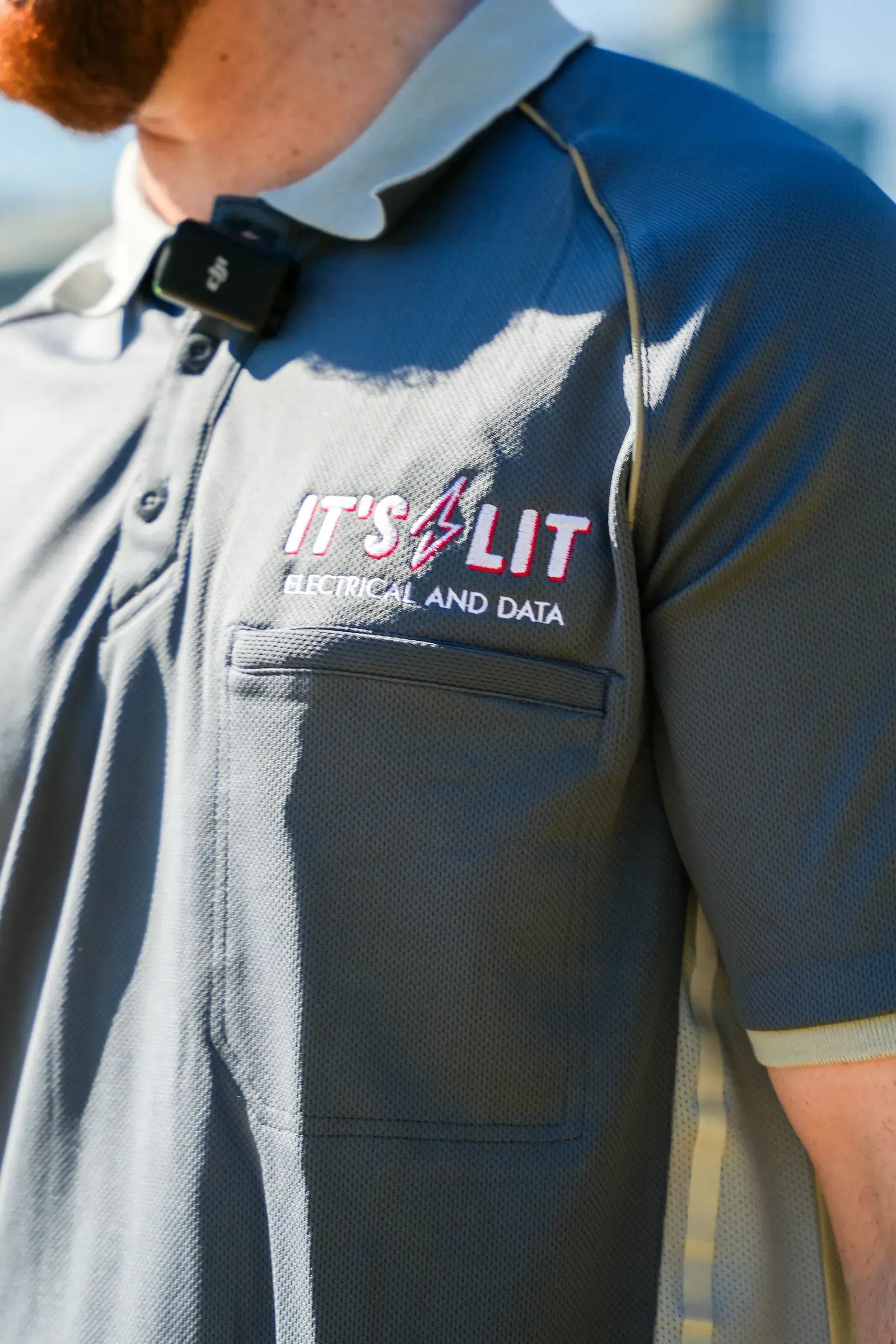 A close-up of a gray polo shirt featuring a logo that reads 