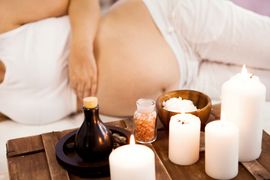 Spa massage scene with candles, oils, and a person lying face down on a table