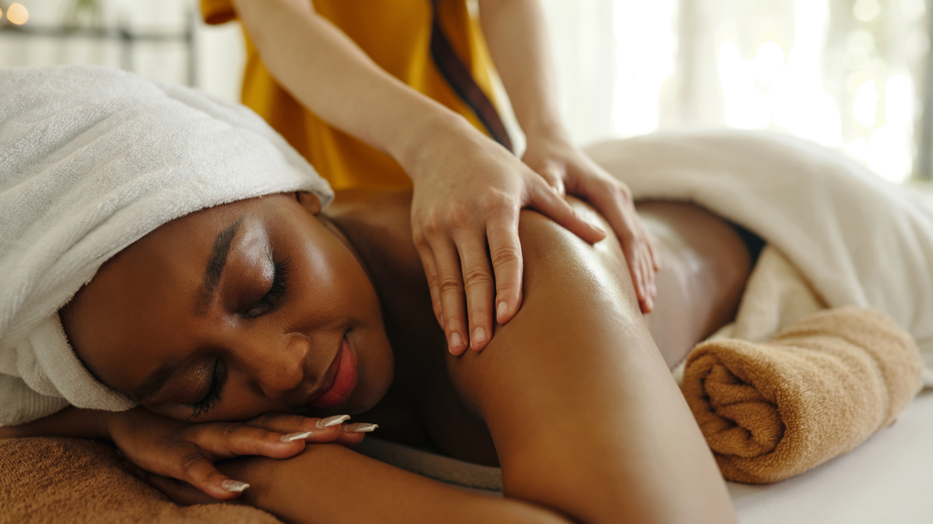 Person resting face down during a massage, with a towel on the head and folded towels nearby