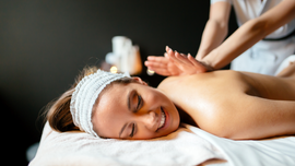 Woman relaxing on a massage table while receiving a back massage in a spa room