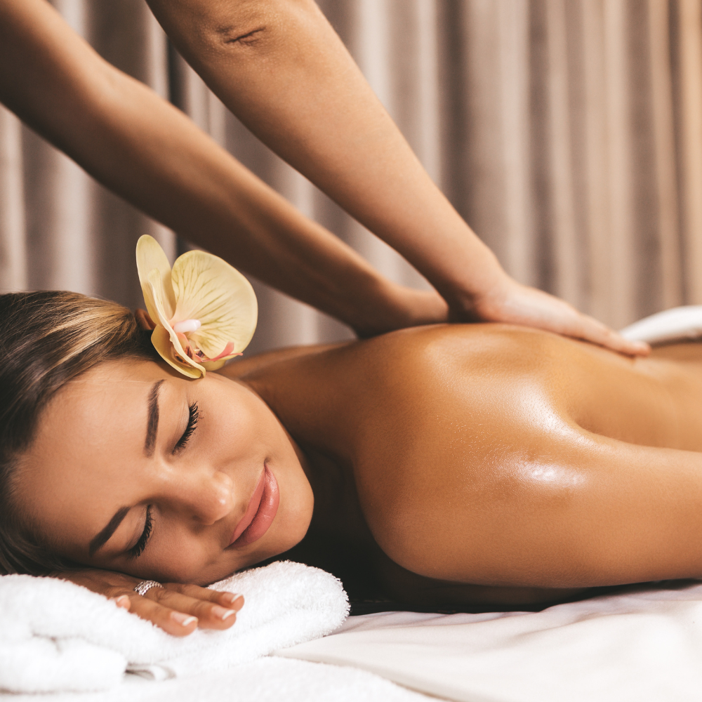 Spa massage with oil, a woman resting on a towel with a flower in her hair