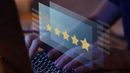 Hand typing on a laptop with a glowing five-star customer rating overlay