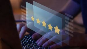 Hand typing on a laptop with a glowing five-star customer rating overlay