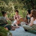 Group sitting in a circle outdoors, talking during a peaceful garden gathering