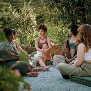 Group sitting in a circle outdoors, talking during a peaceful garden gathering