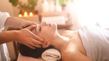 Spa therapist giving a facial massage to a client lying on a treatment table