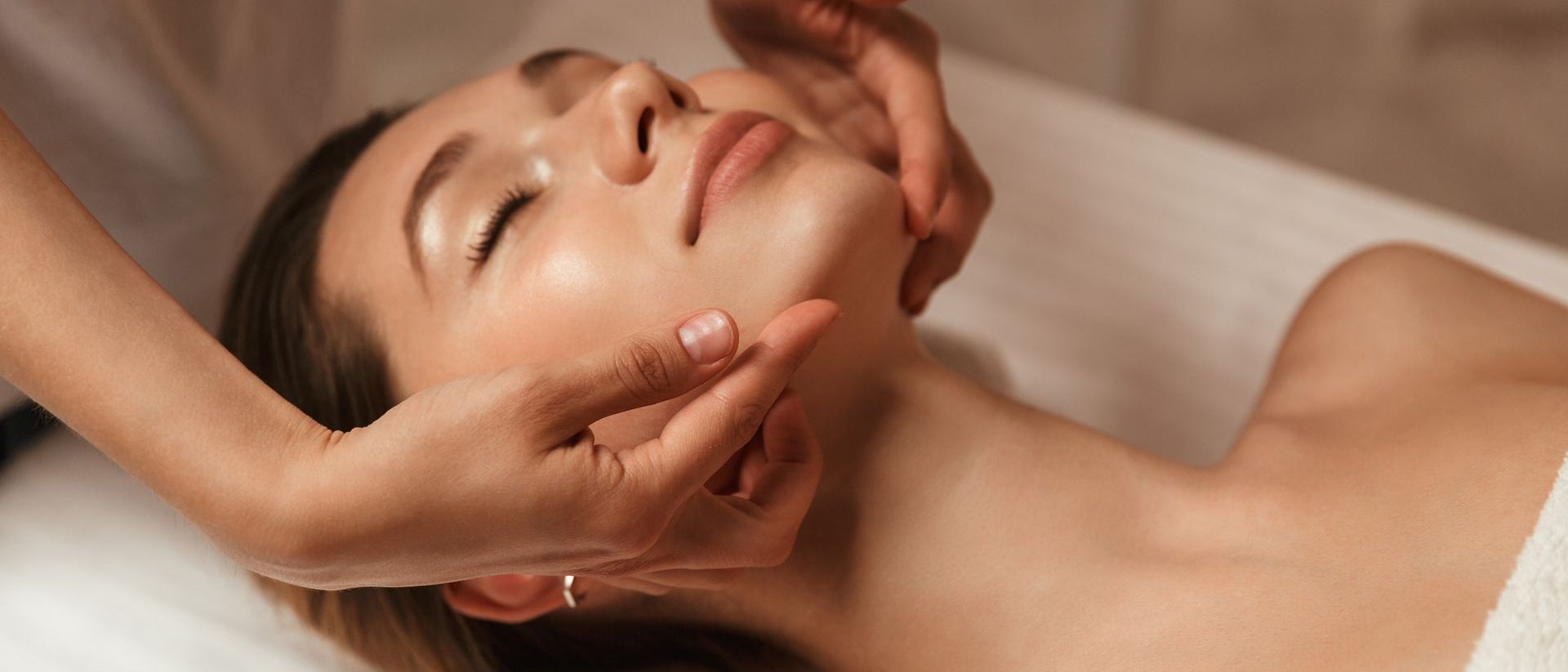 A woman is getting a facial massage at a spa.