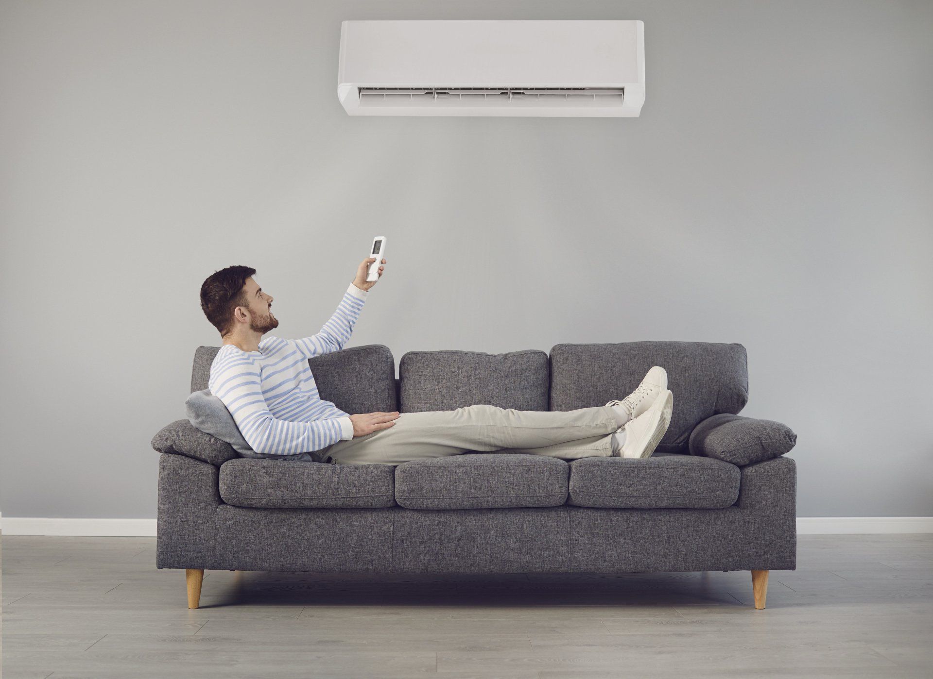 A man is laying on a couch holding a remote control.